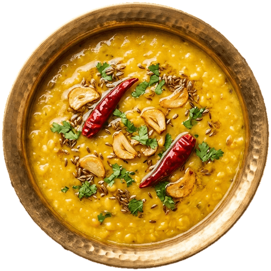 Seen from above: dal tadka in a brass bowl, with garlic, cumin and two dried red chillies